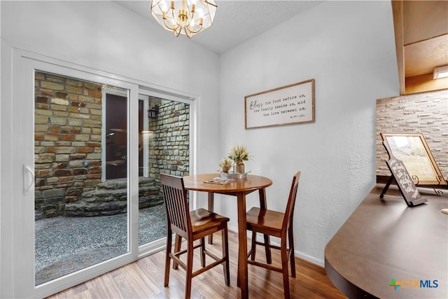 dining area with wood-type flooring and a notable chandelier