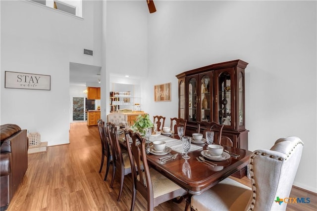 dining area with light hardwood / wood-style floors and a towering ceiling