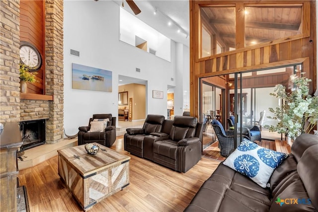 living room with hardwood / wood-style floors, beam ceiling, a fireplace, and high vaulted ceiling