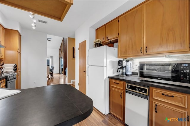 kitchen featuring light wood-type flooring, stainless steel appliances, tasteful backsplash, and rail lighting