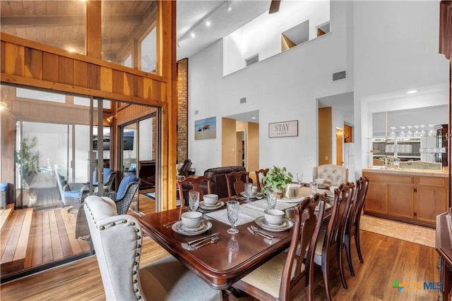 dining area with beam ceiling, light hardwood / wood-style floors, and high vaulted ceiling