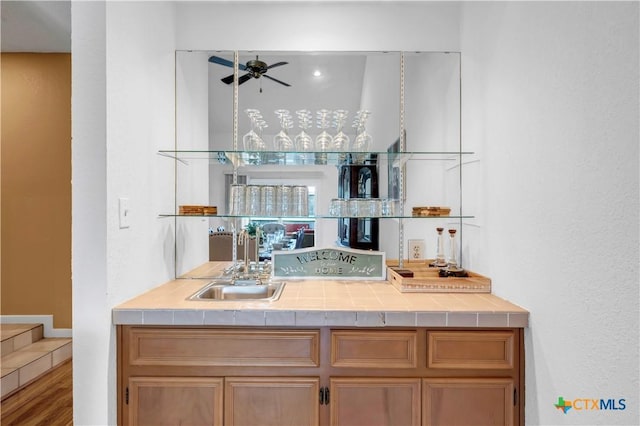 bar featuring hardwood / wood-style flooring, ceiling fan, and sink