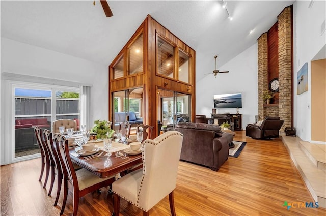 dining space featuring light wood-type flooring, high vaulted ceiling, and ceiling fan