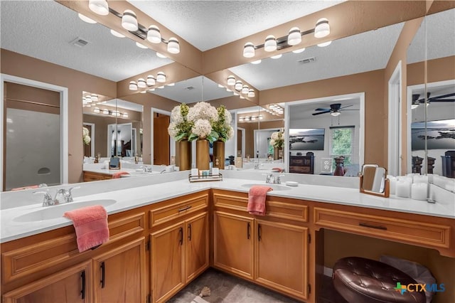 bathroom featuring vanity, ceiling fan, and a textured ceiling