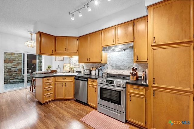 kitchen with kitchen peninsula, a textured ceiling, stainless steel appliances, sink, and light hardwood / wood-style floors