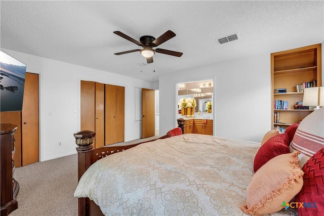 bedroom featuring a textured ceiling, light colored carpet, ceiling fan, and connected bathroom