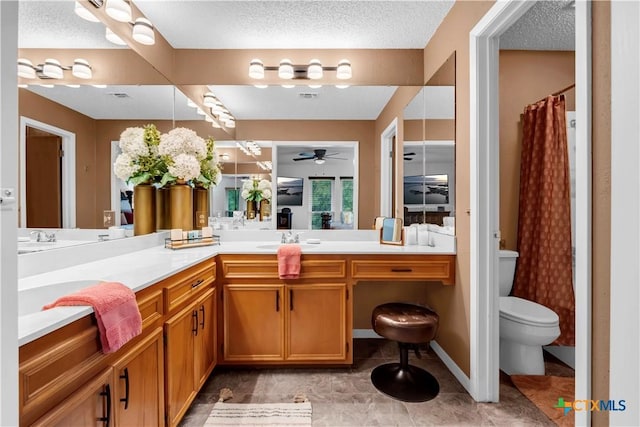 bathroom with vanity, a shower with curtain, ceiling fan, toilet, and a textured ceiling