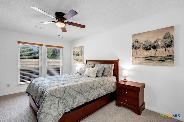 carpeted bedroom featuring ceiling fan and a textured ceiling