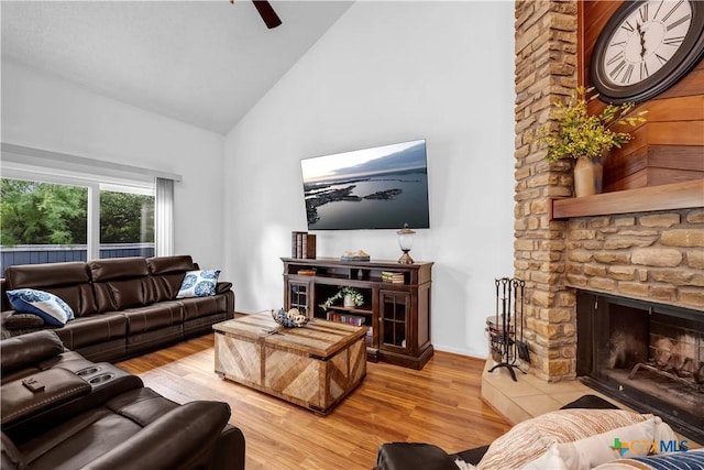 living room with a fireplace, light hardwood / wood-style floors, high vaulted ceiling, and ceiling fan