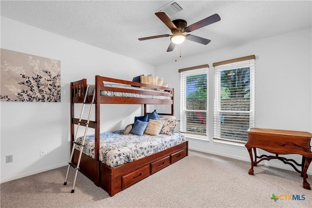 carpeted bedroom with ceiling fan and a textured ceiling