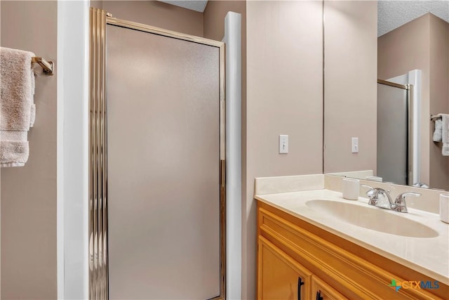 bathroom with vanity, a textured ceiling, and a shower with door