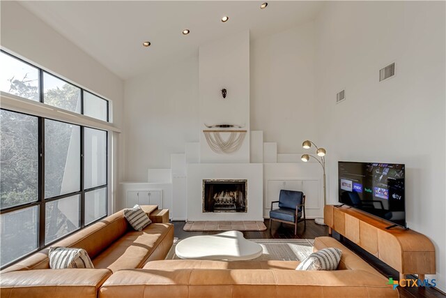 living room with visible vents, a towering ceiling, wood finished floors, a fireplace, and recessed lighting