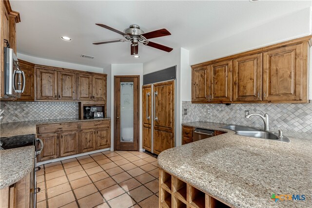 kitchen featuring brown cabinets, light tile patterned floors, stainless steel appliances, visible vents, and a sink