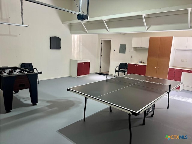 game room featuring a garage, a sink, baseboards, finished concrete flooring, and electric panel