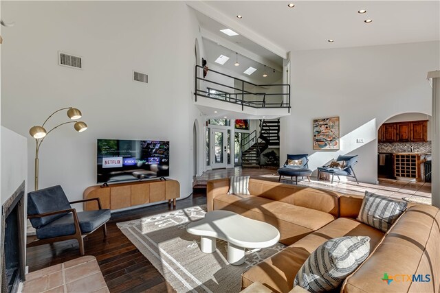 living area with stairway, visible vents, arched walkways, and wood finished floors