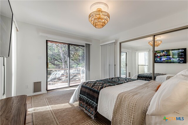 bedroom with access to outside and an inviting chandelier