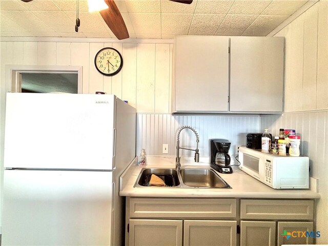 kitchen featuring sink, wooden walls, and white appliances