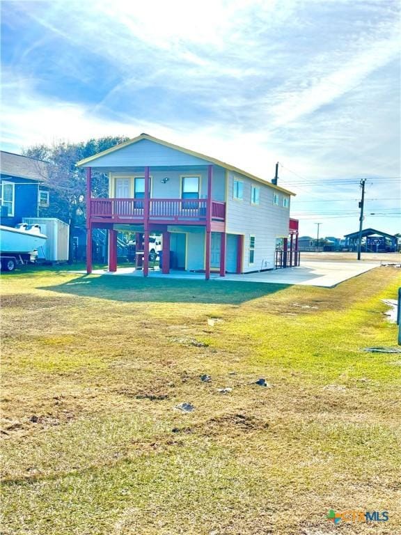 rear view of house featuring a balcony and a yard