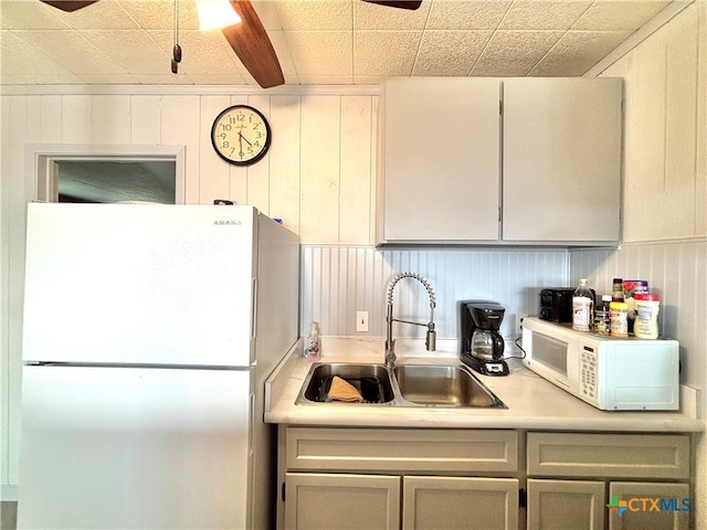 kitchen featuring sink, wooden walls, and white appliances