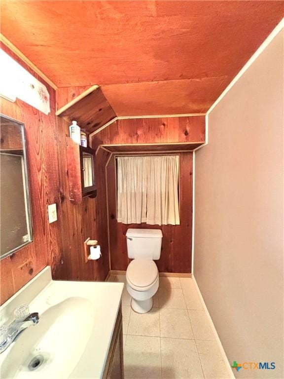 bathroom with vanity, tile patterned flooring, wooden walls, and toilet