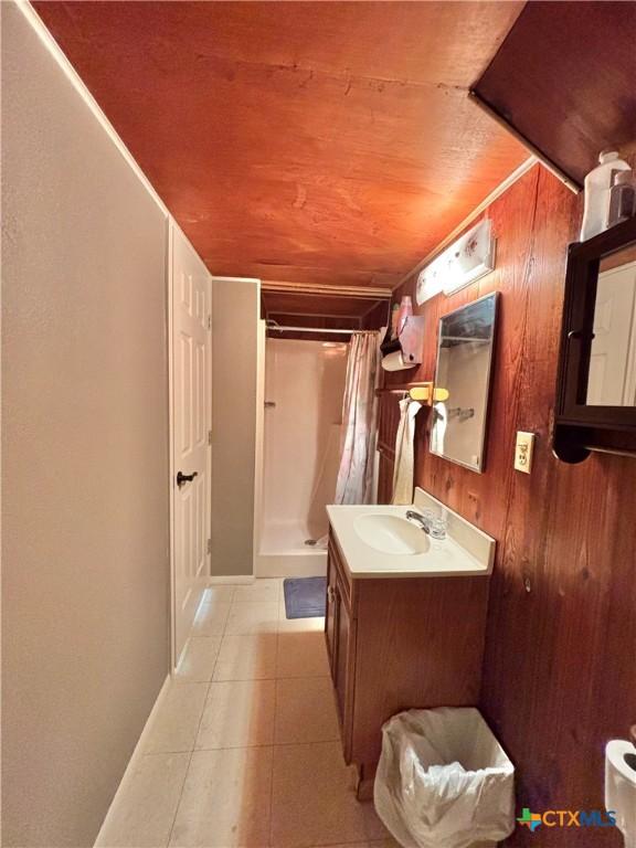 bathroom with wooden ceiling, curtained shower, vanity, and wood walls