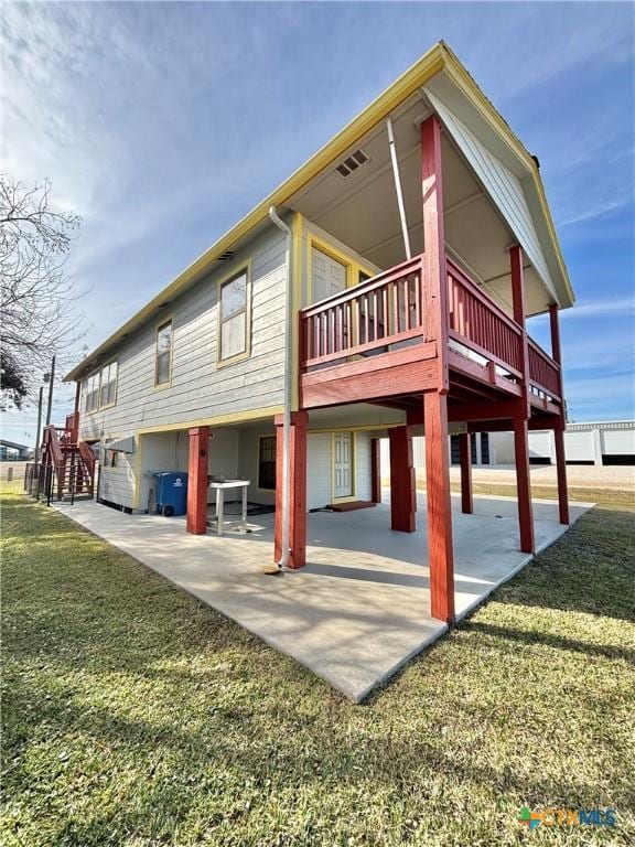 rear view of house with a wooden deck, a yard, and a patio area