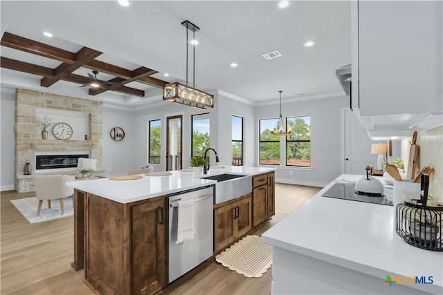 kitchen featuring decorative light fixtures, an island with sink, sink, coffered ceiling, and stainless steel dishwasher