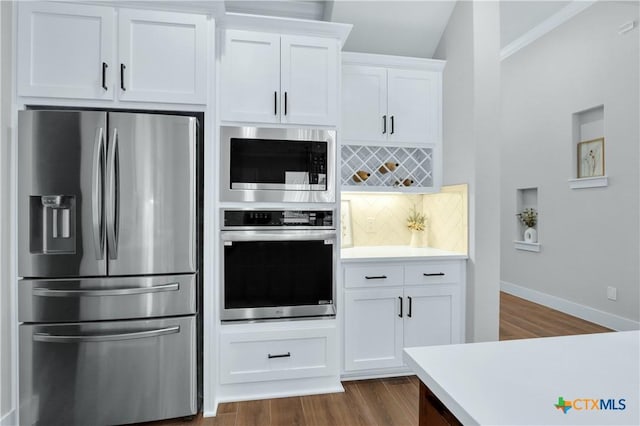 kitchen with dark wood-type flooring, backsplash, white cabinetry, and stainless steel appliances