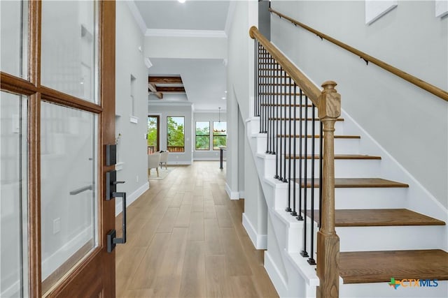 foyer with beamed ceiling, ornamental molding, and light hardwood / wood-style floors