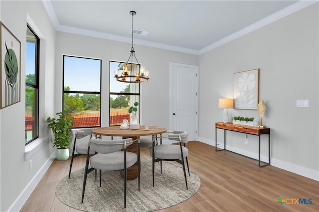 dining area with an inviting chandelier, ornamental molding, and light wood-type flooring