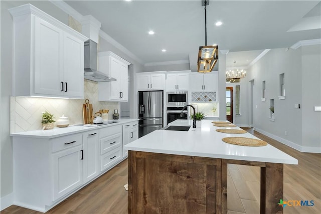 kitchen featuring sink, appliances with stainless steel finishes, hanging light fixtures, an island with sink, and white cabinets