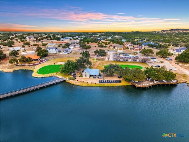 aerial view at dusk featuring a water view