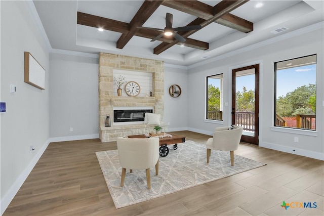 living room with a fireplace, beamed ceiling, hardwood / wood-style flooring, coffered ceiling, and ceiling fan