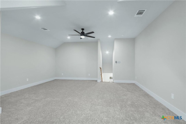 spare room featuring light carpet, vaulted ceiling, and ceiling fan