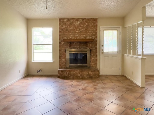 1804 Kingman Rd, Killeen, TX 76549 - unfurnished living room with a textured ceiling, plenty of natural light, tile patterned floors, and a brick fireplace