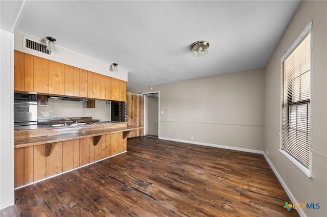 3105 Julie Ln, Killeen, TX 76549 - kitchen with oven, a breakfast bar, dark wood-type flooring, a peninsula, and baseboards
