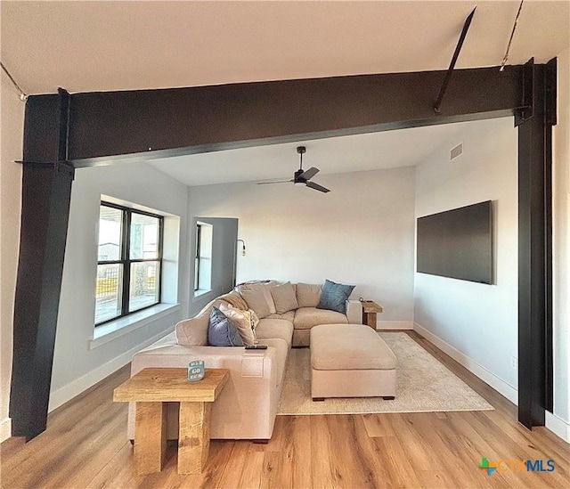 living room with ceiling fan, beam ceiling, and light hardwood / wood-style floors