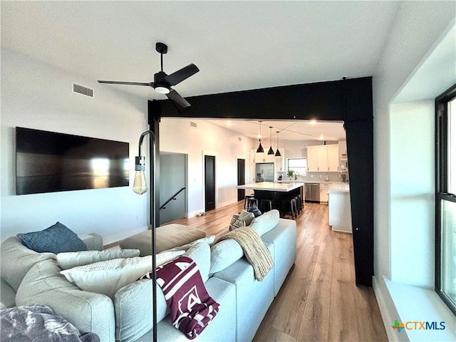 living room featuring vaulted ceiling, ceiling fan, and light wood-type flooring