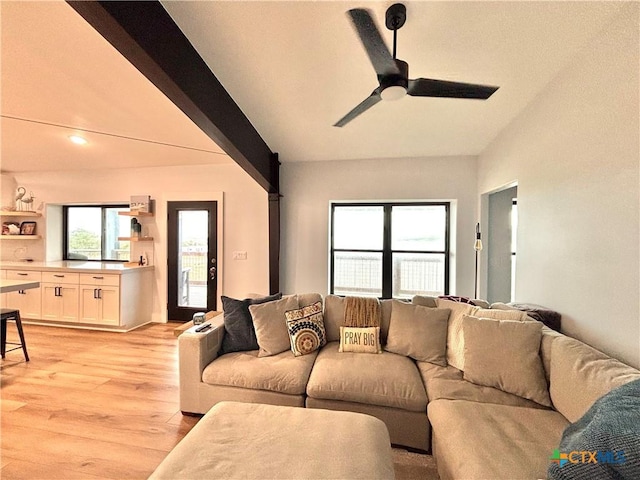 living room featuring ceiling fan, beamed ceiling, and light wood-type flooring