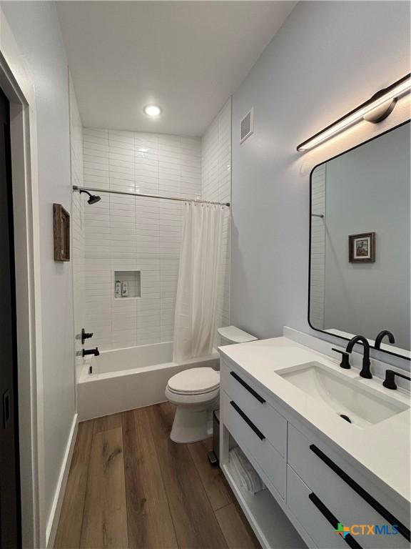 full bathroom with vanity, hardwood / wood-style flooring, toilet, and shower / bath combo with shower curtain