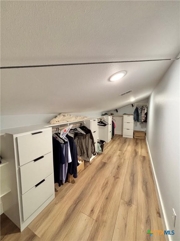 spacious closet featuring vaulted ceiling and light wood-type flooring