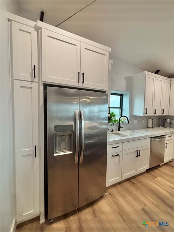 kitchen featuring sink, light hardwood / wood-style flooring, stainless steel appliances, and white cabinets