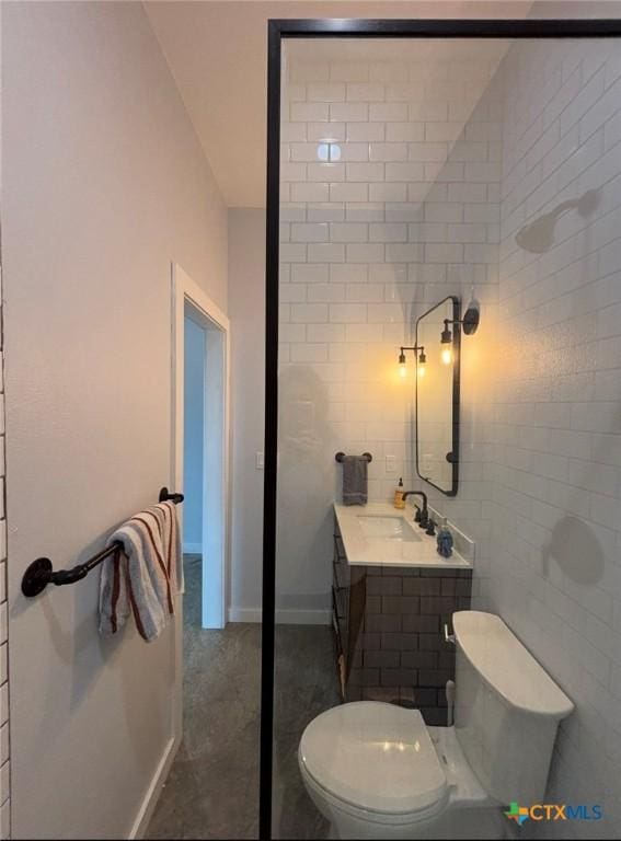 bathroom with vanity, toilet, and tile walls