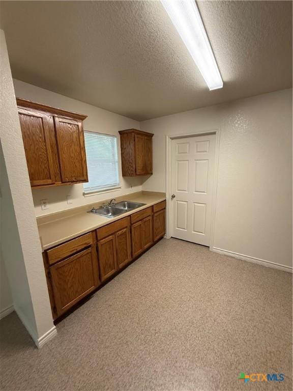 705 N 2nd St, Temple, TX 76501 - kitchen featuring a sink, brown cabinets, light countertops, a textured ceiling, and baseboards