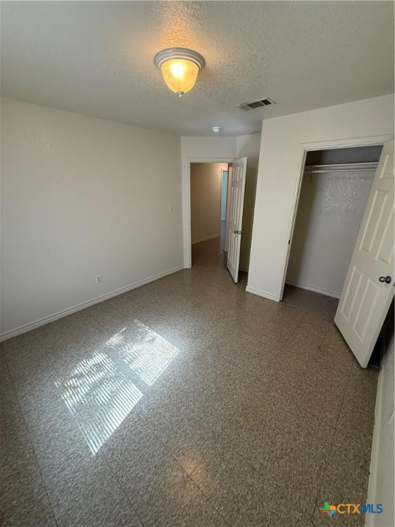 705 N 2nd St, Temple, TX 76501 - unfurnished bedroom with baseboards, a textured ceiling, and a closet