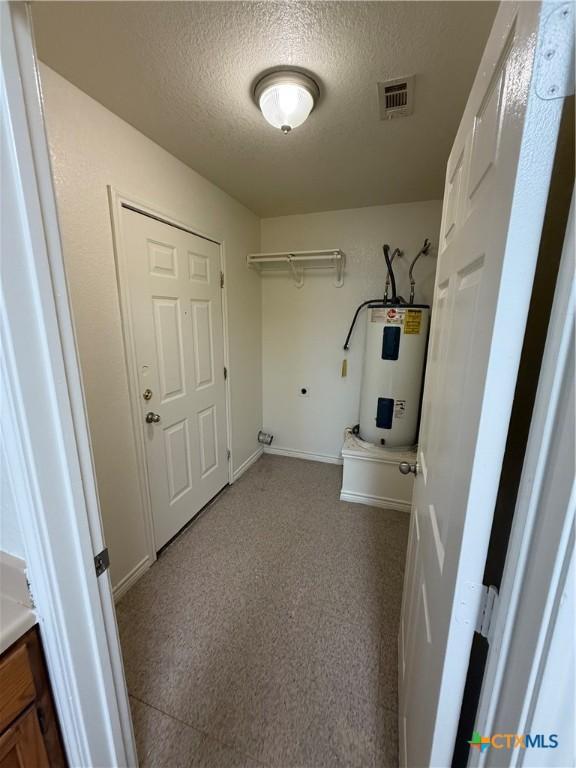 705 N 2nd St, Temple, TX 76501 - washroom featuring electric water heater, a textured ceiling, and baseboards