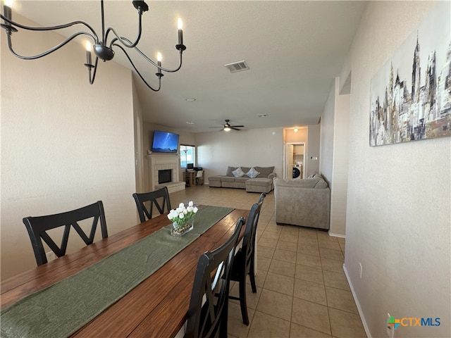 tiled dining area with ceiling fan with notable chandelier