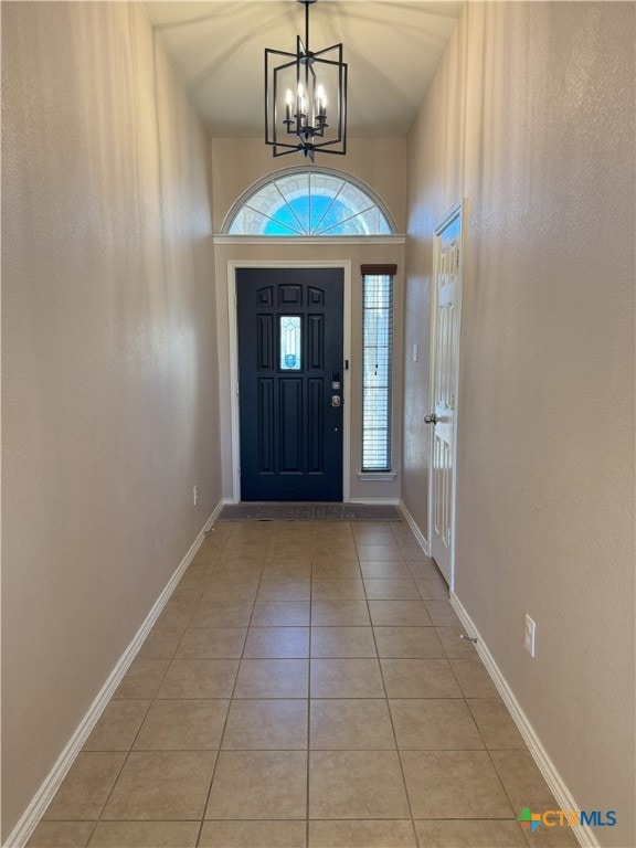 tiled entryway with a notable chandelier