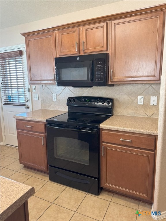 kitchen featuring black appliances, decorative backsplash, and light tile patterned flooring