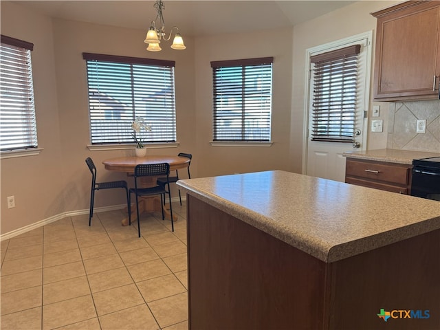 kitchen with hanging light fixtures, backsplash, light tile patterned floors, a healthy amount of sunlight, and a notable chandelier